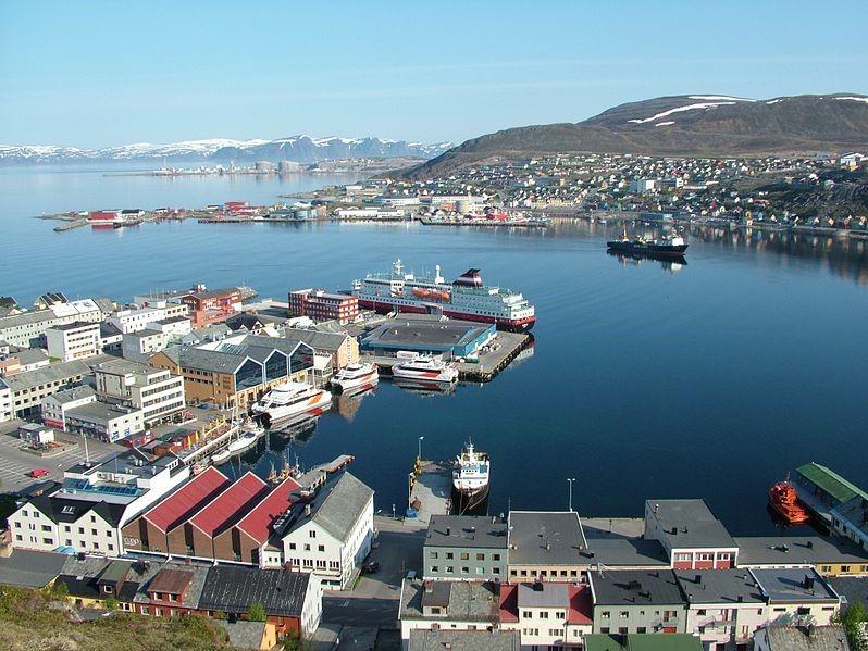 Hammerfest by på ein klar og stille dag. Hurtigruta ligg til kai i hamna. I bakgrunnen ser vi LNG-anlegget på Melkøya. Foto.