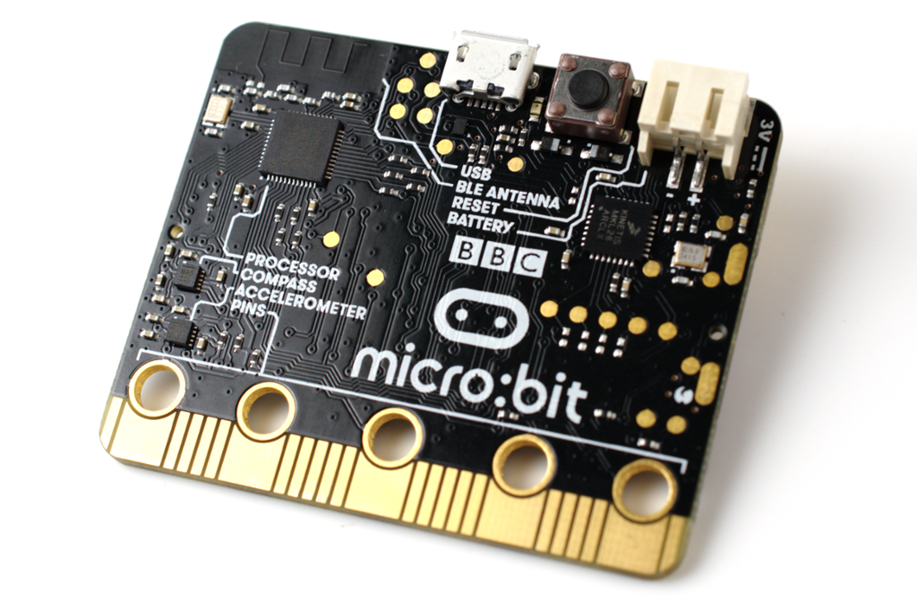 Mikrokontroller frå micro:bit. Han er ei firkanta brikke i svart og gult. Storleiken er fire gonger fem centimeter. Fotografi.