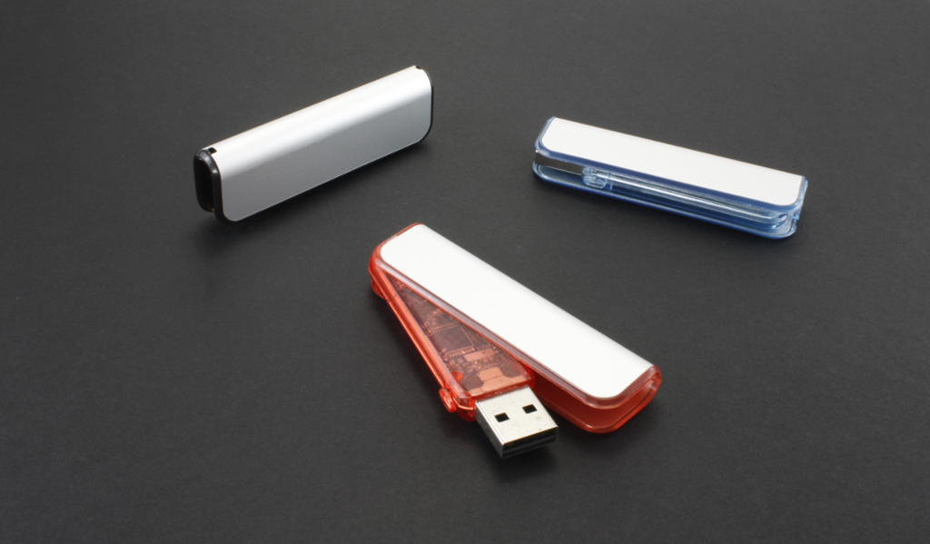 Tre USB-minnepenner ligger på en overflate. Foto.