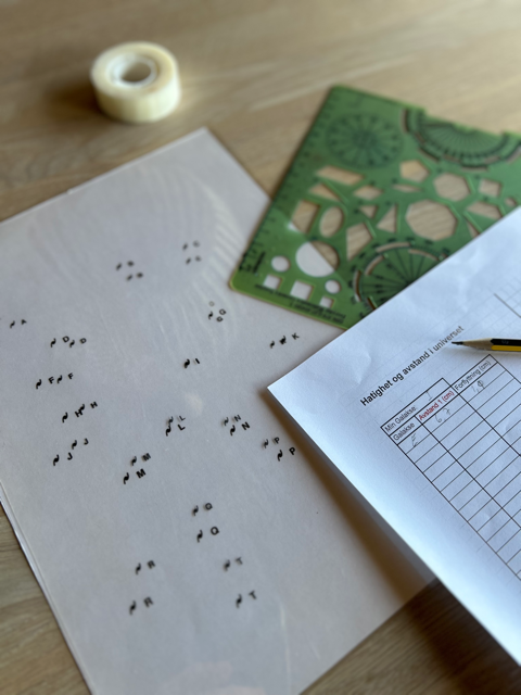Et ark med tabell, et ark med punkter merket med bokstaver, linjal og teip ligger på et bord. Foto