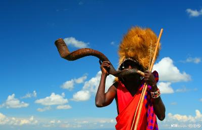 Masaikriger som spiller på tradisjonelt horn. Foto.