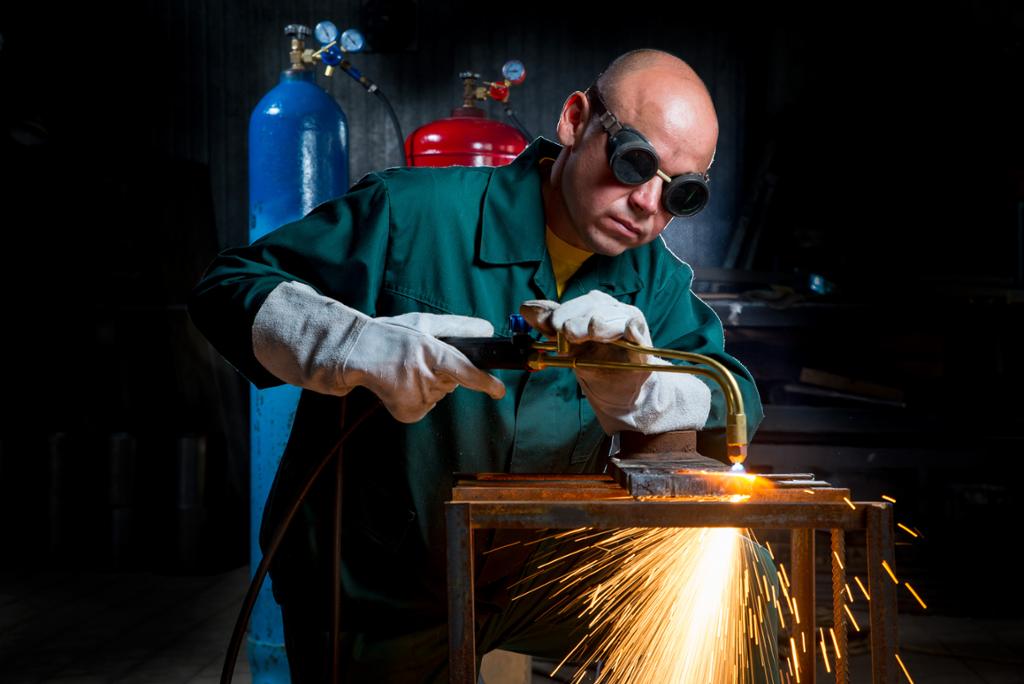 Person som skjærer metall med en skjærebrenner. Foto.