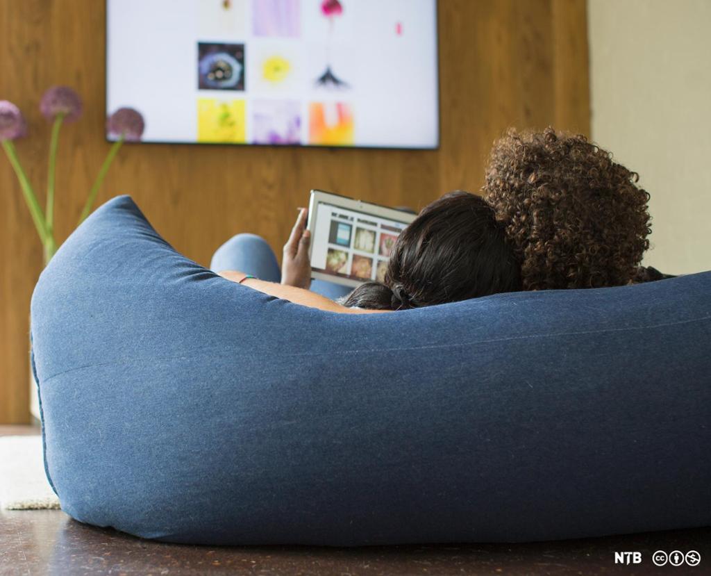 Photo: Young couple relaxing streaming photos from digital tablet to TV.