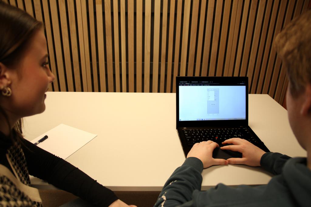 To personer ser på en skisse av en app på en laptop. Foto. 