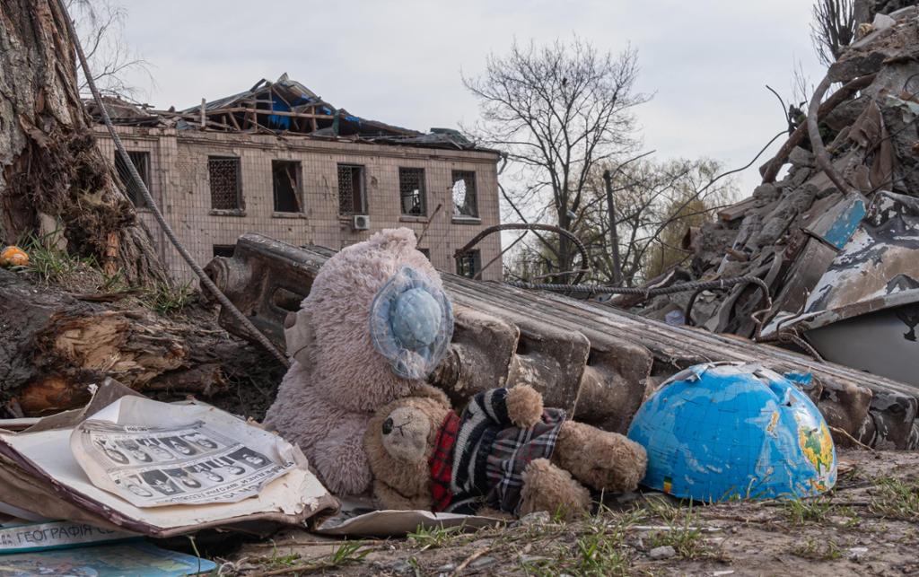 Photo: Buildings destroyed by bombs. In the foreground we see two teddy bears and half a globe. 