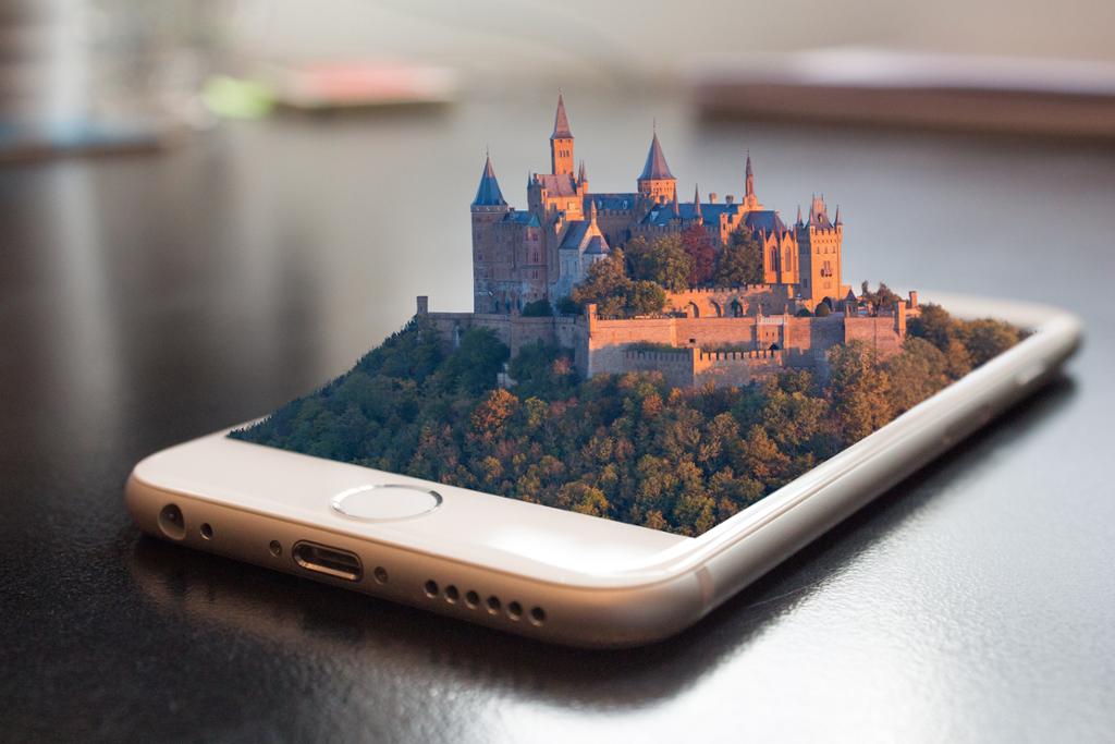 Augmentet Reality i skjermen på ein mobiltelefon. Eit 3D-bilete av eit slott i ein skog veks ut av skjermen. Illustrasjon.