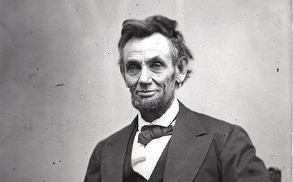 Photo: Abraham Lincoln. We see an older man with a thin face, a beard, and ruffled hair. 