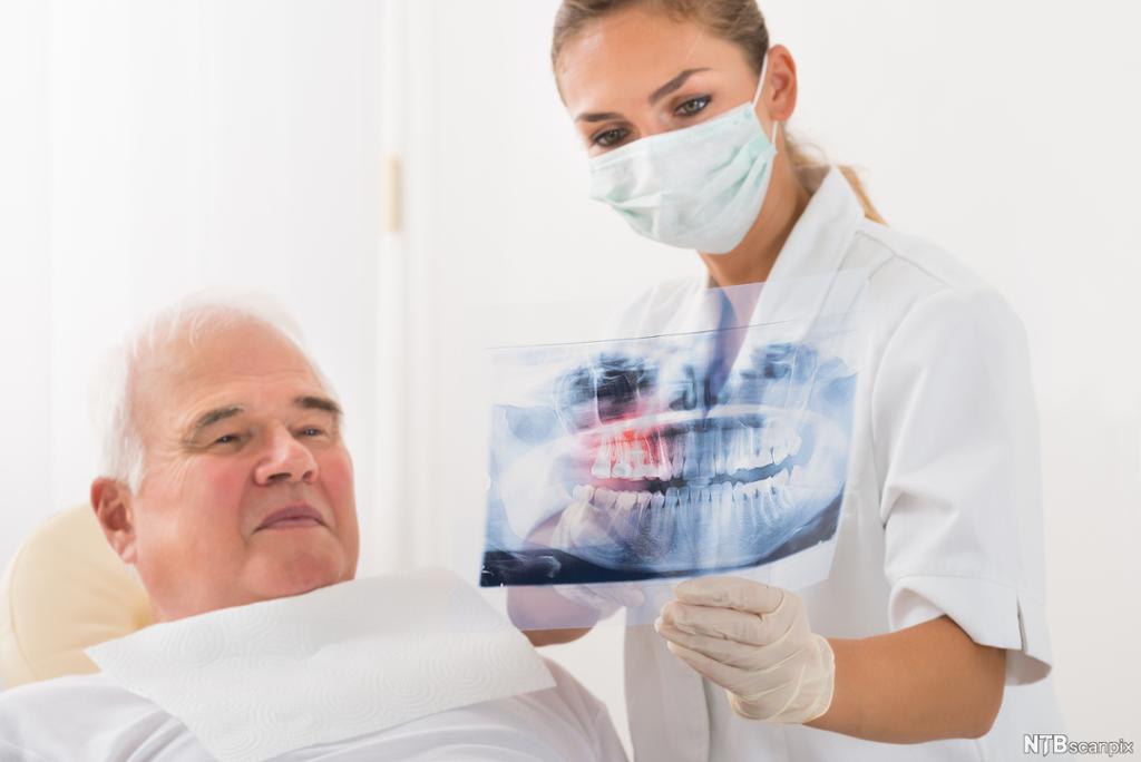 Tannlege viser røntgenbilde til pasient. Foto.