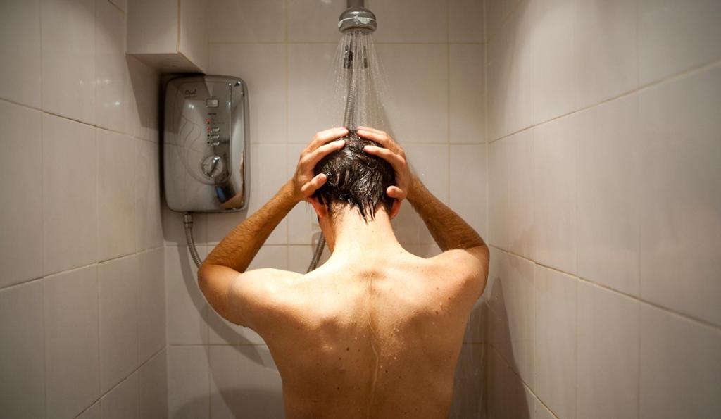Mann som står i dusjen. Foto. 
