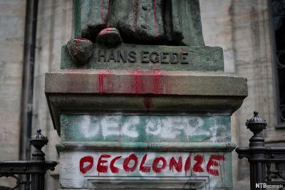Sokkelen til statuen av Hans Egede i Grønland med ordet "decolonize" sprayet med rød maling. Foto