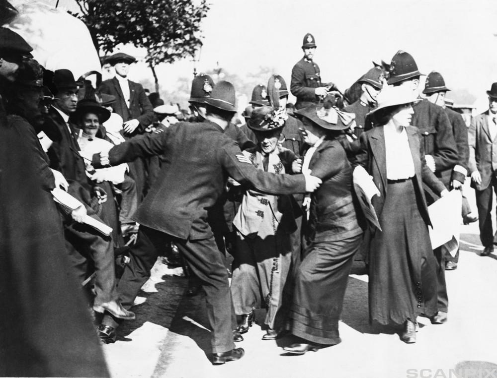 Black and white photo of Emmeline Pankhurst and her daughters are being arrested at a demonstration. 