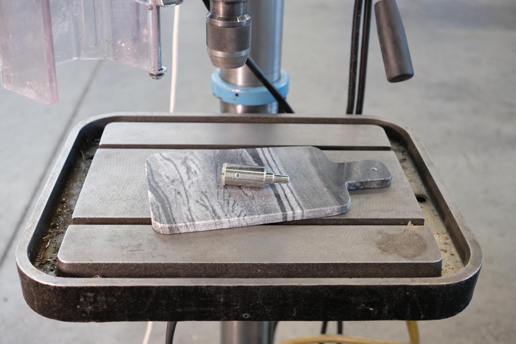 Diamantbor (kjernebor) på et marmorbrett. Bor og brett ligger oppå arbeidsbordet til en maskin. Foto.