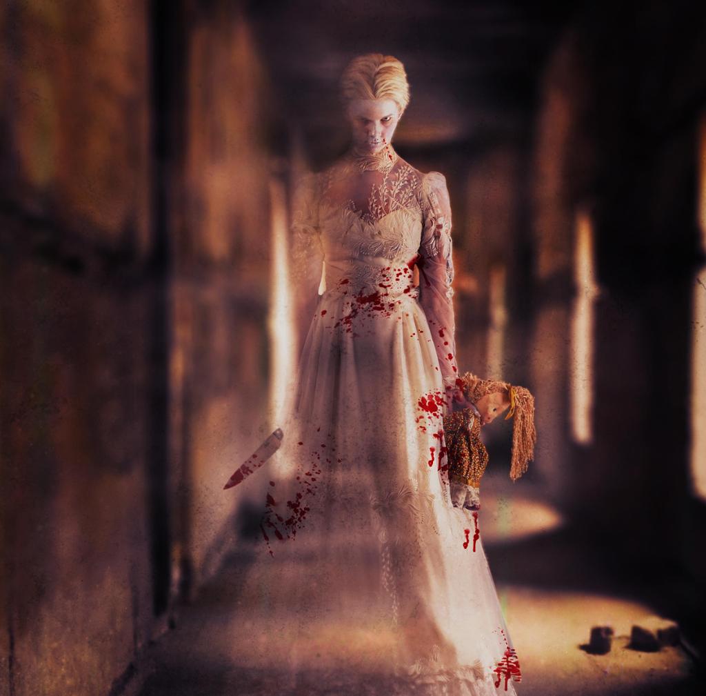 Photo: A blonde woman in a wedding dress. She is partly transparent. She is carrying a doll and a knife.  