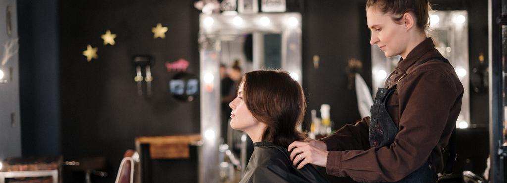 Kvinneleg frisør arbeider med håret til ein kvinneleg kunde. Foto.
