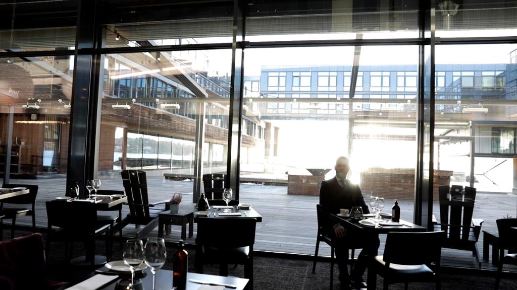 Mann sitter alene i en restaurant ved et tomannsbord. Foto.