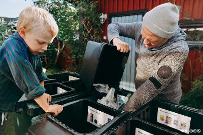 En voksen og et barn sorterer søppel sammen. Foto.