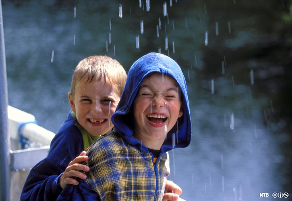 To gutar som er ute i regnet utan regnklede og har det veldig morosamt. Foto. 