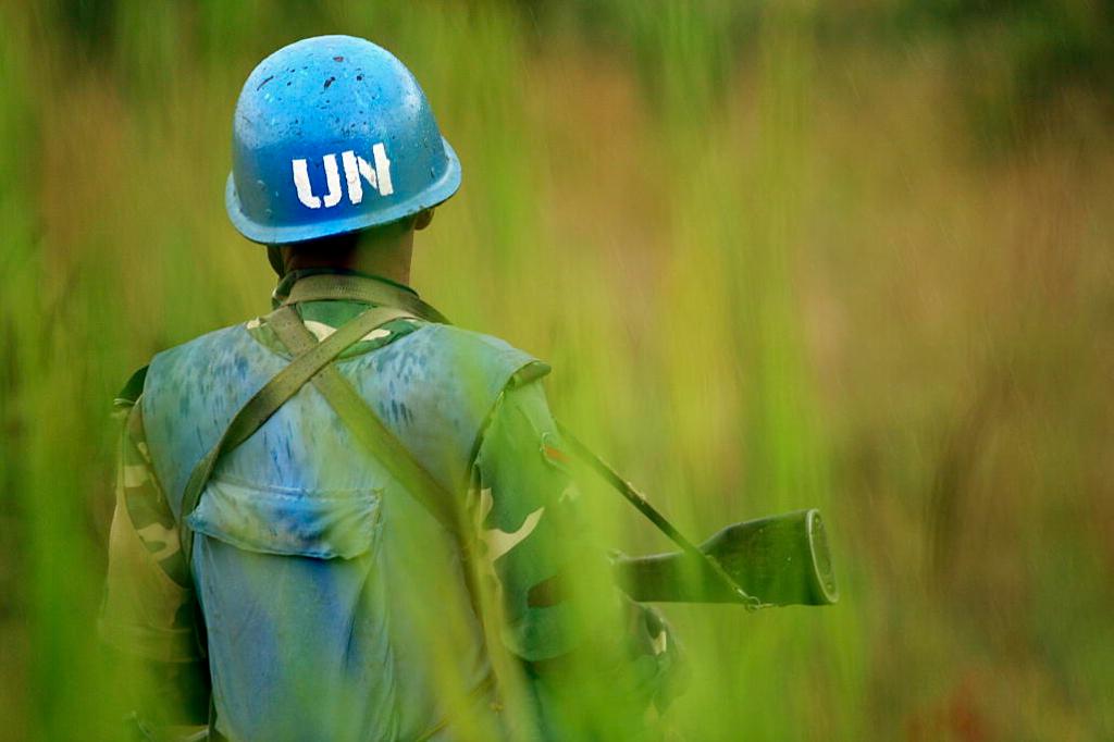 En FN-soldat med våpen står vakt. Han har hjelm på seg. Foto. 