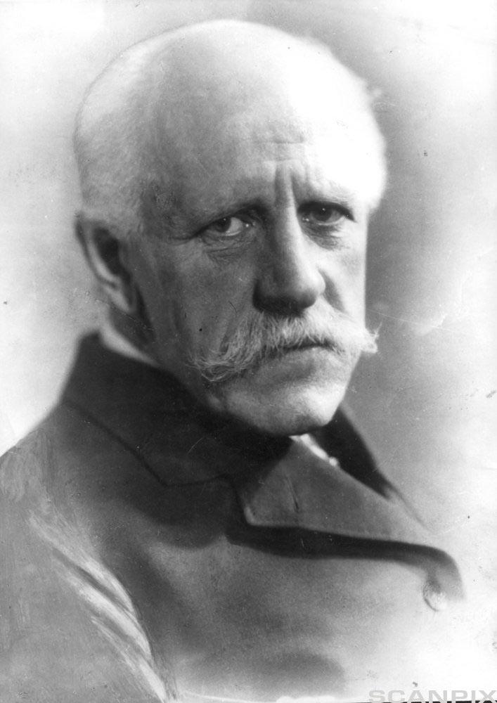 Portrett av ein eldre mann med kvitt hår og bart. Han har frakk på seg. Mannen er Fridtjof Nansen. Svart-kvitt foto. 