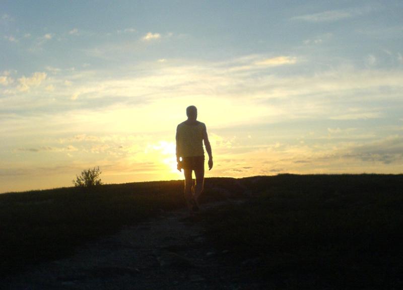 En mann går i solnedgangen. Foto.