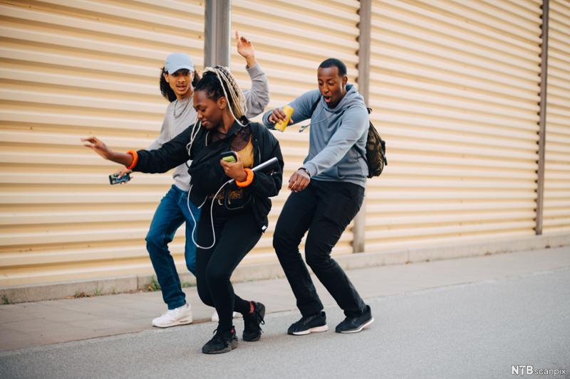 Tre ungdommer danser på gata. Foto.