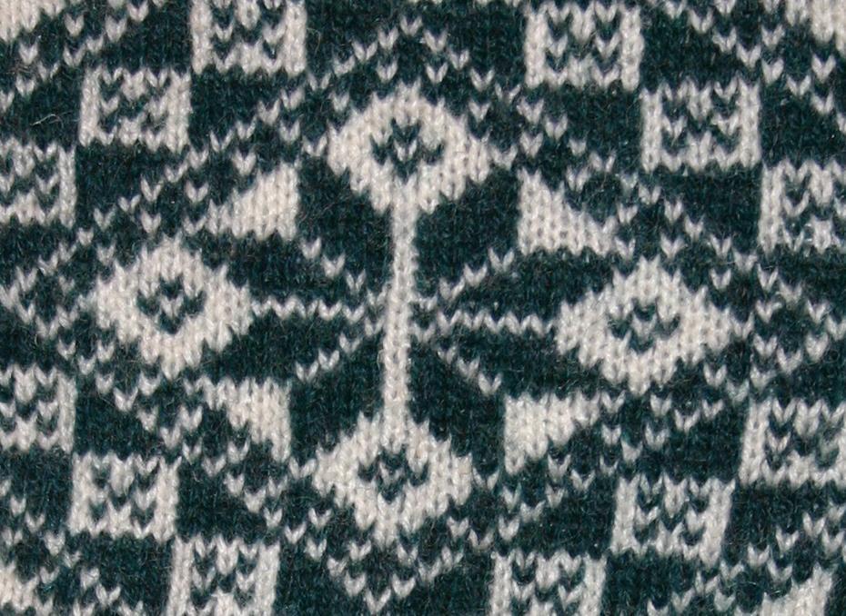 Strikkemønster med åttebladrosei mørkegrønt og kvitt. Foto.
