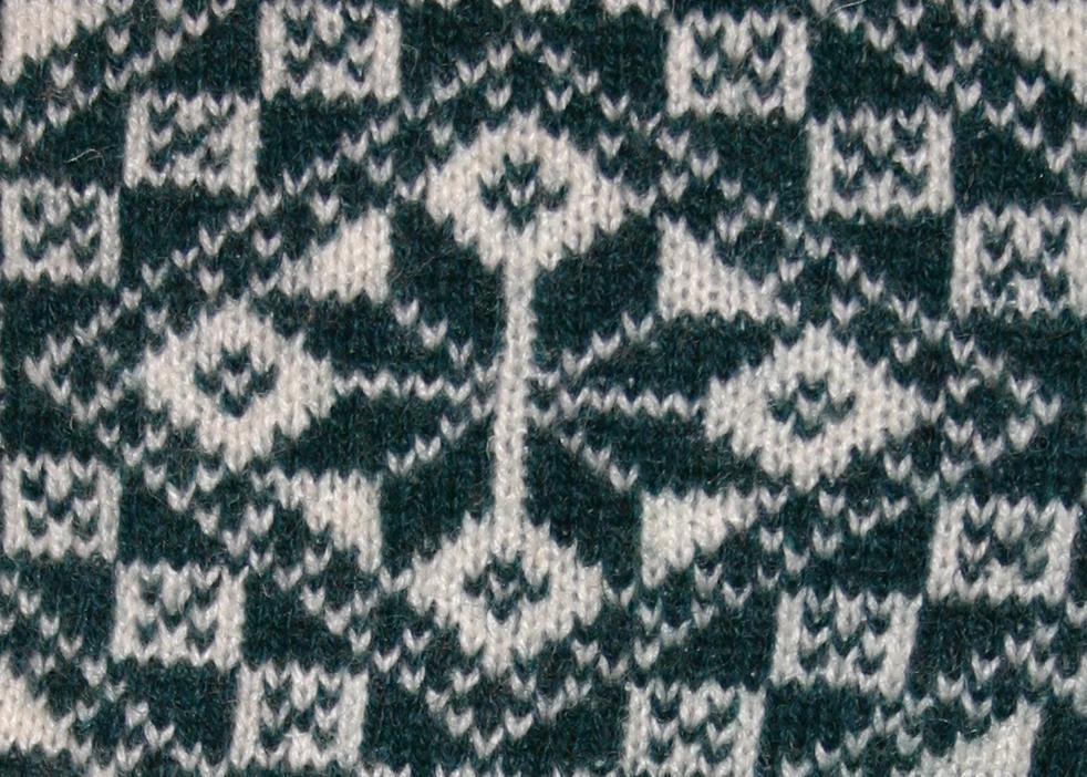 Strikkemønster med åttebladrose i mørkegrønt og hvitt. Foto.