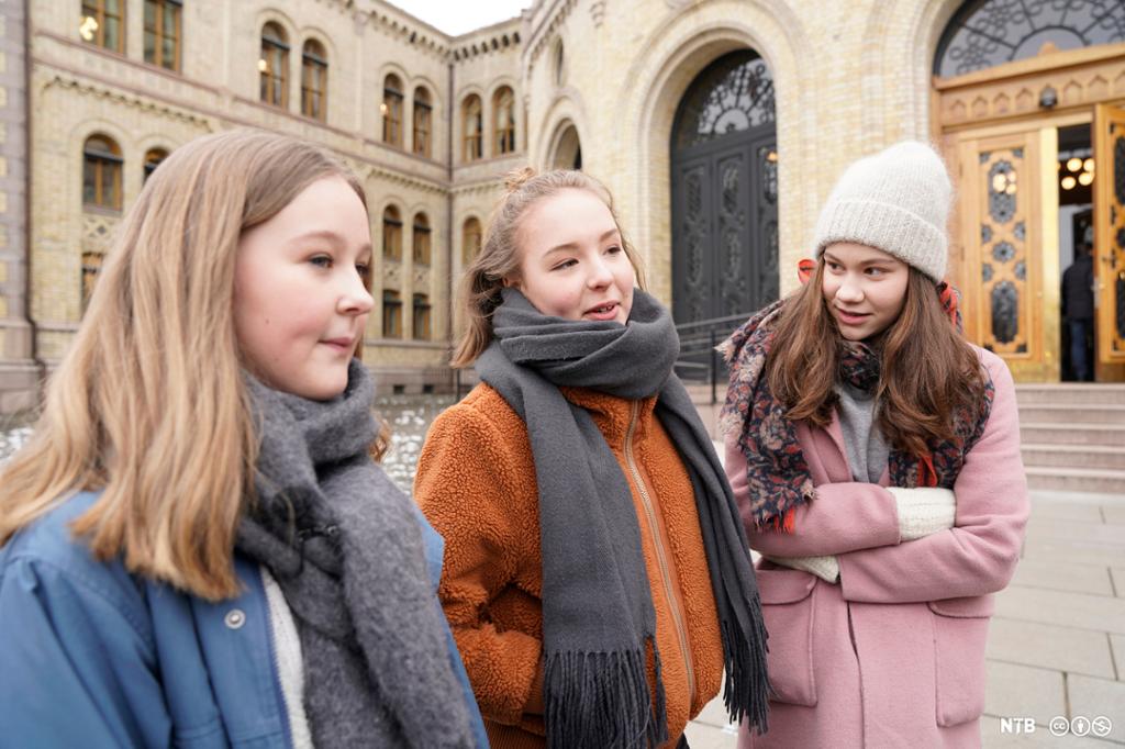 Tre fjortenårige jenter står foran Stortinget. Foto.