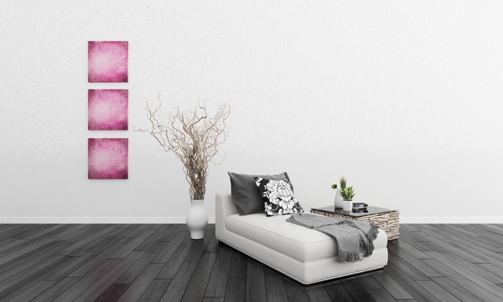 Sjeselong med puter og pledd og tre rosa bilder på veggen. Foto. 