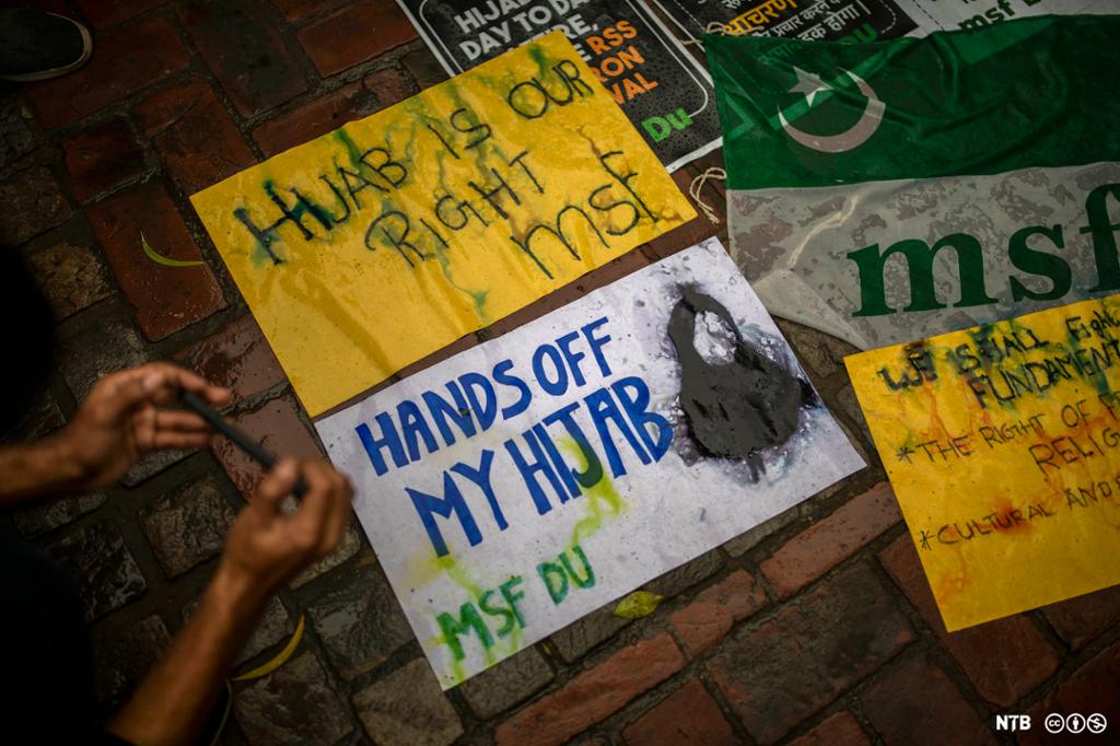 Plakatar ligg på bakken med påskrifta " Hands off my hijab". Foto.
