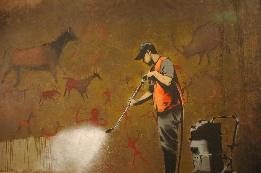 A mural of a man using a high pressure washing to wash off cave paintings. Photo.