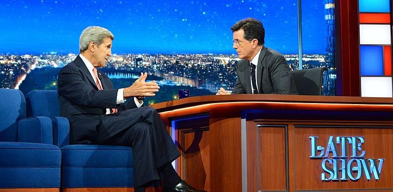 Secretary John Kerry makes an appearance on The Late Show with Stephen Colbert. The two men are sitting on either side of a desk, in deep conversation. 