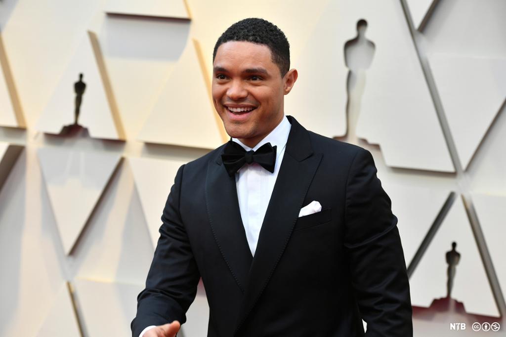 Photo: Trevor Noah at the Academy Awards. He is wearing a tuxedo and black bow tie. He is a young man who is smiling. 