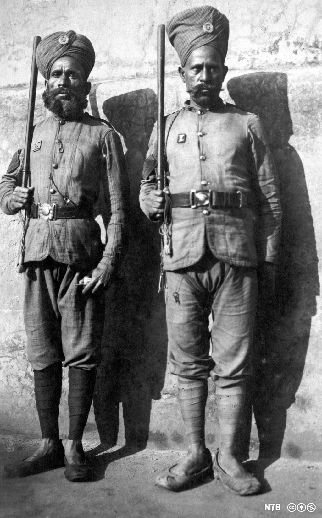 Two armed and uniformed prison guards standing next to a wall, Rangoon, Burma. 