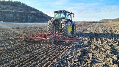 Traktor som kjører på et jorde med en slodd. Foto. 