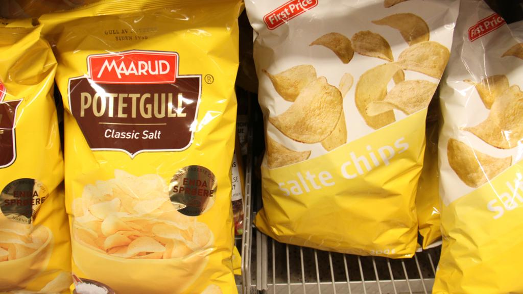 Poser med salt potetgull i to ulike prisklasser og av to ulike merker, Maarud og First Price, side om side i en butikkhylle. Foto.
