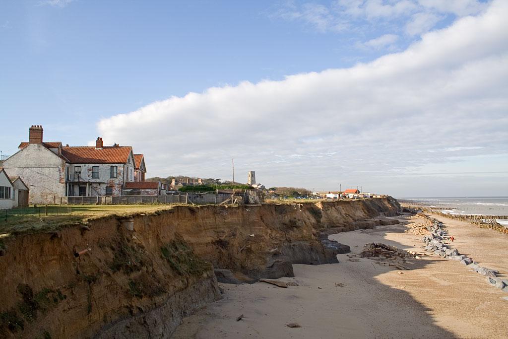 Kyst hvor hus er truet av havet.