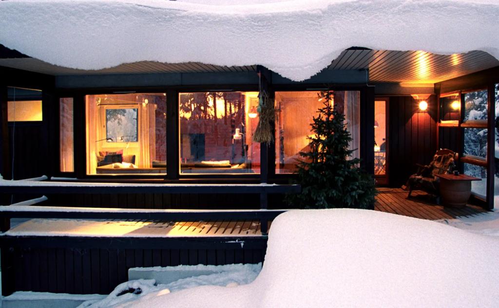 Hus med store vinduer og mye snø på taket. Foto.