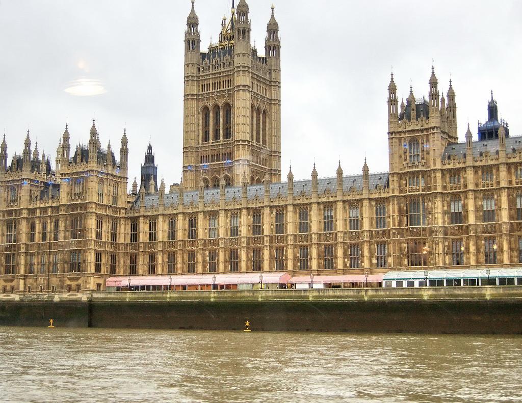 Photo: The Palace of Westminster in London, which is home to the British Parliament. We see a large old building with towers and turrets. The building has many windows. 