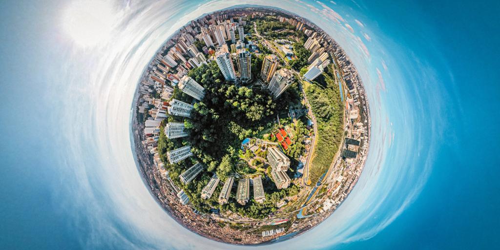 360-graders bilde tatt med drone over en by, slik at den ligner en klode. Foto.