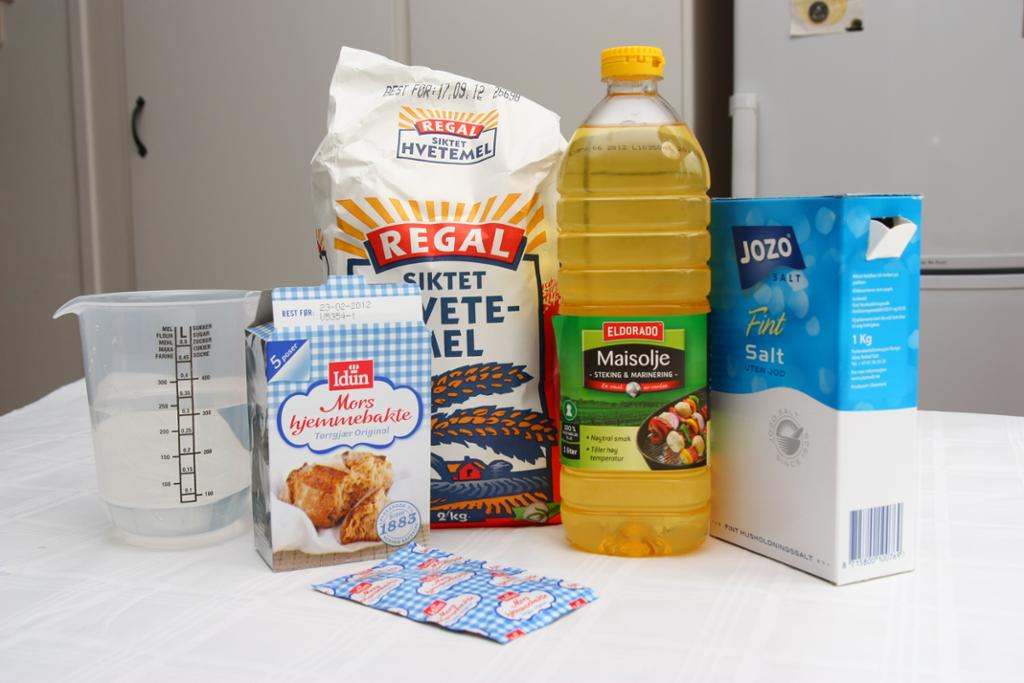 Melpose, pakke med gjær, flaske med maisolje, litermål med vann og en boks med salt på et bord. Foto.