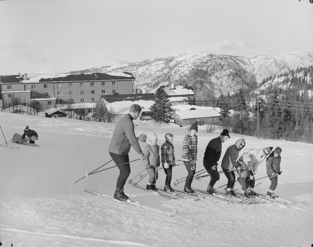 Voksne og barn på ski i vinterlandskap. Foto.