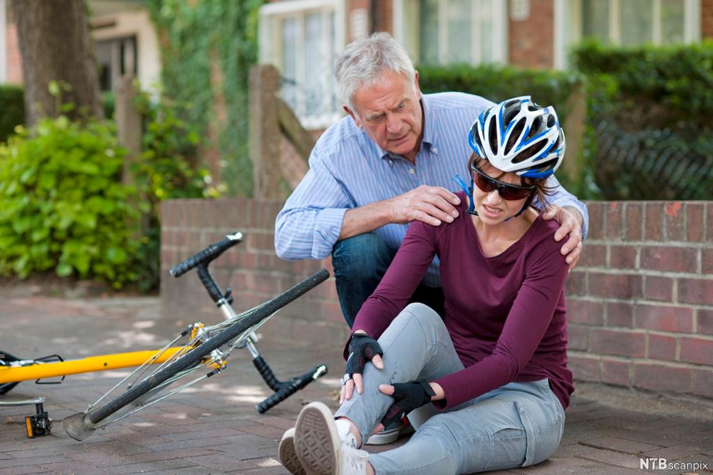 Ein mann viser omsorg for ei dame som har velta på sykkel. Foto. 