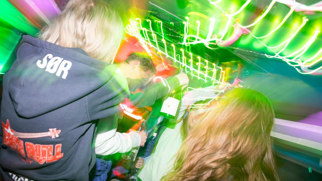 Gutter og jenter i russedresser fester og drikker sammen i en russebuss. Foto.