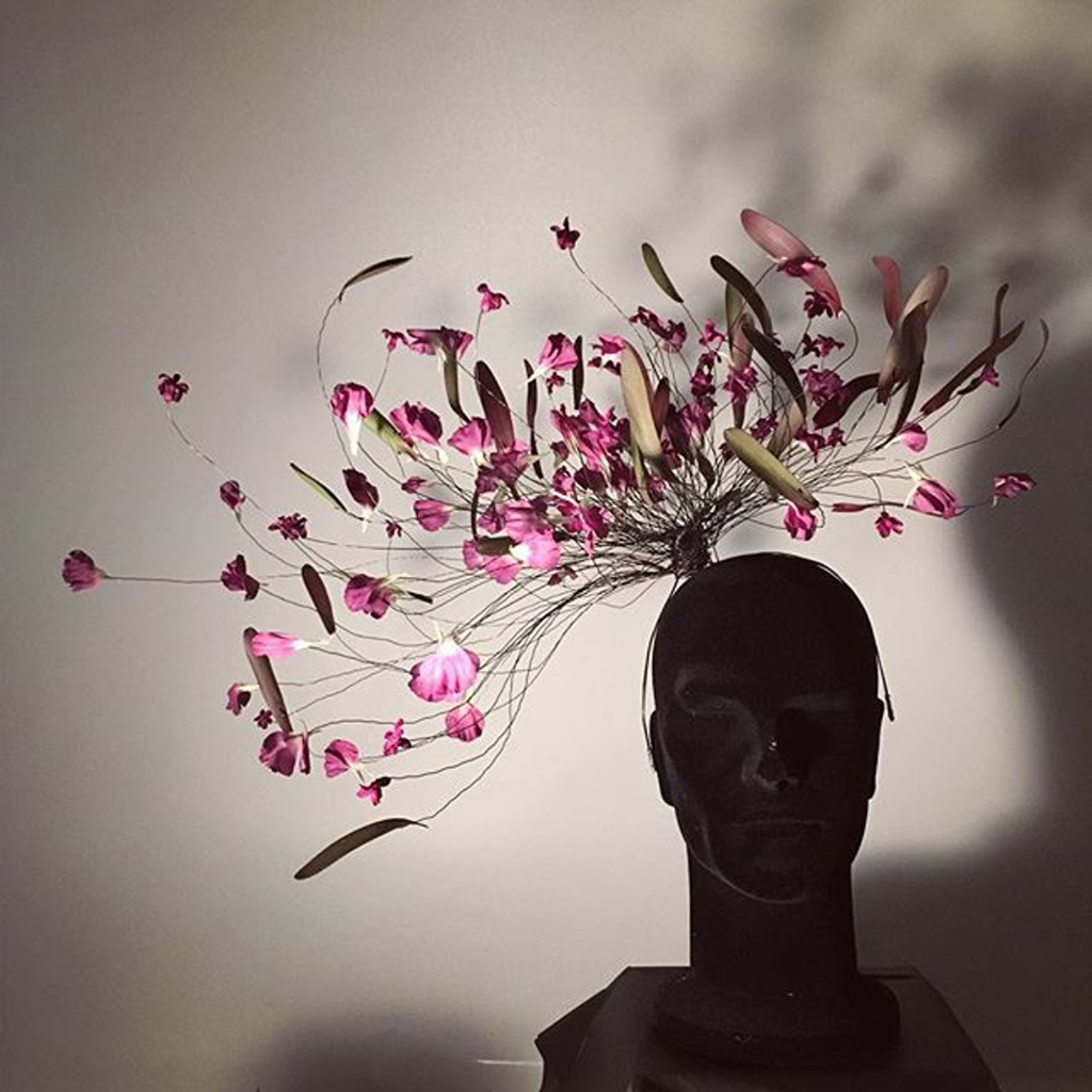 Byste med et hodeplagg laget av ståltråder og blomster. Foto.