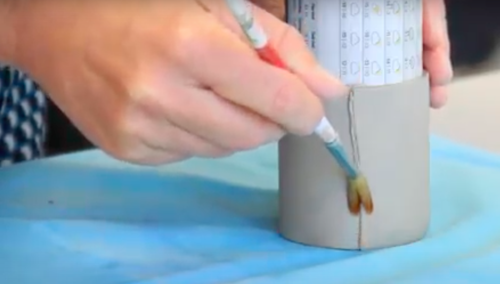 Hender fjerner overflødig slikker i skjøten med en pensel. Foto.