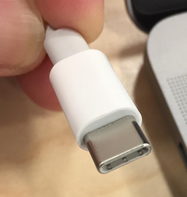Nærbilde av ein kvit USB-C kontakt ved siden av ein bærbar datamaskin. Foto