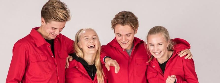 Fire ungdommer i røde russedresser holder rundt hverandre og smiler. Foto.