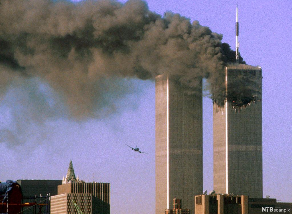 Den eine skyskraparen på World Trade Center er treft og står i brann. Det kjem mykje røyk. Eit fly har kurs rett mot det andre tårnet. Foto.