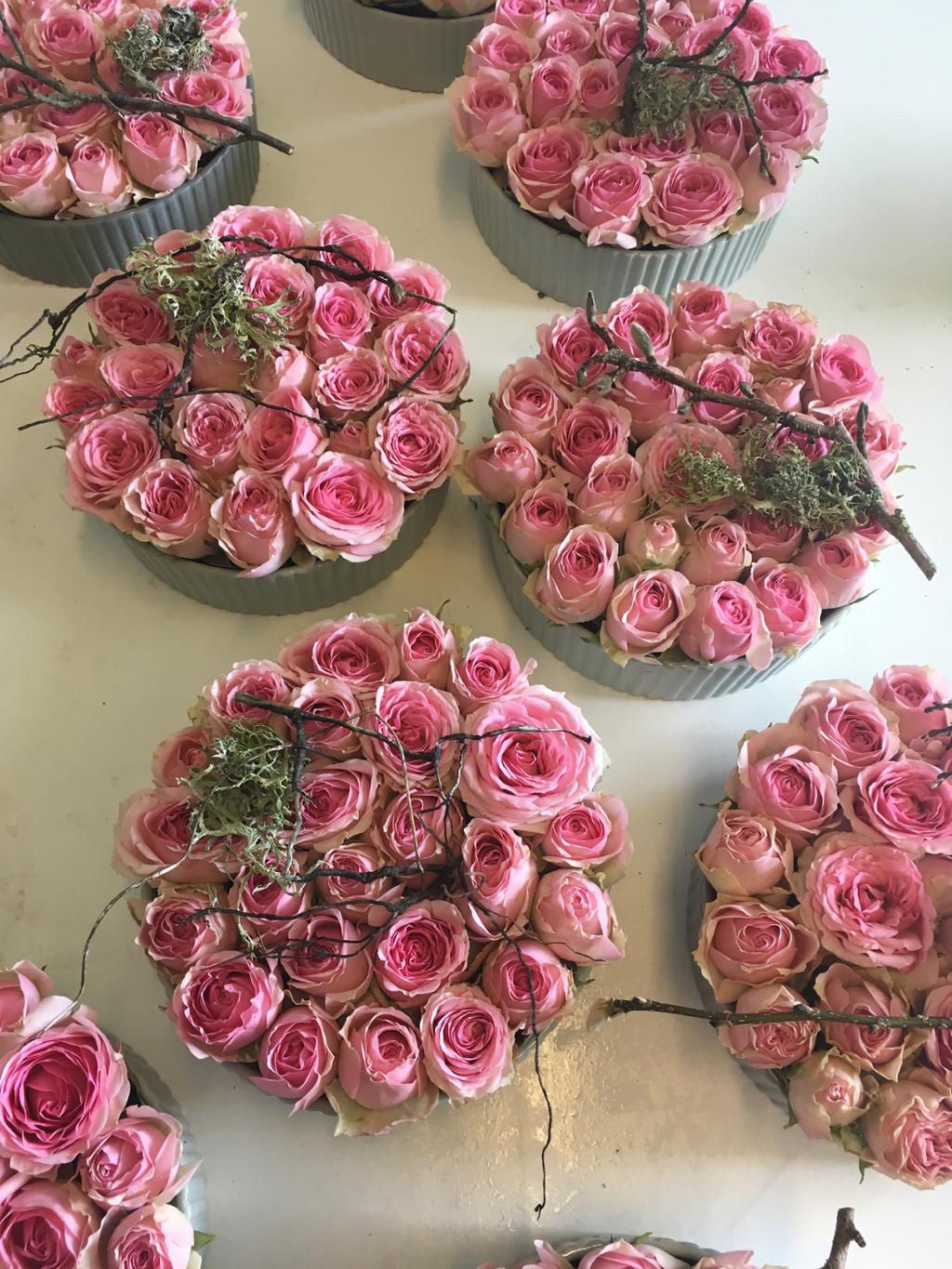 Runde blomsterdekorasjoner laga av rosa roser og kvistar. Foto.